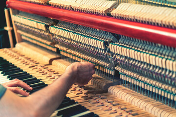 Piano tuning process. closeup of hand and tools of tuner working on grand piano. Detailed view of Upright Piano during a tuning. toned