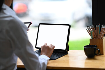 Cropped shot of bussinesswoman working on computer tablet and smartphone with blank screen in her office.