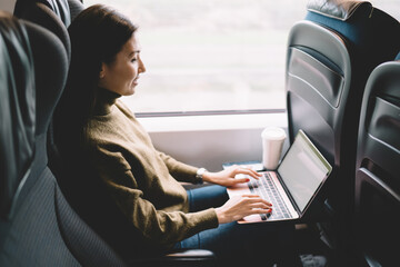 Cheerful lady resting in train with laptop