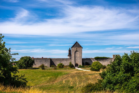 Beautiful rural summer view of an ancient medieval brick tower and defense wall surrounding the city of Visby Gotland, Sweden. Blue sky and grassy fields.
