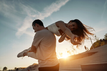 Happy couple. Man carrying woman on his back. On the Sunset