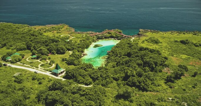 Indonesia landmark of salt water jade lake Weekuri at Sumba Island. Epic resort at limpid loch with natural variety. Amazing architecture attraction with road and cars at green tropic plants, trees