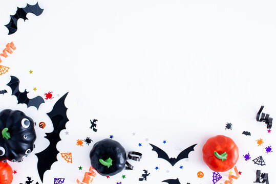 Halloween background on white. Halloween frame made with pumpkins, bats, web and spiders. Festive confetti. 