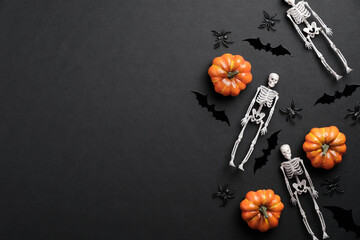 Happy Halloween banner mockup. Flat lay composition with skeletons, pumpkins, bats on black background. Top view with copy space.