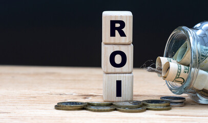 ROI - abbreviation on cubes on the background of a capacity with money