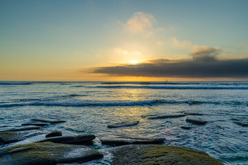 Naklejka premium A sunset from a rocky shore along the coast of California.
