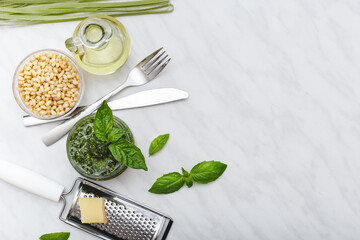 Pesto sauce with ingredients: pine nuts, basil, olive oil, parmesan, cutlery, Raw green fettuccine...