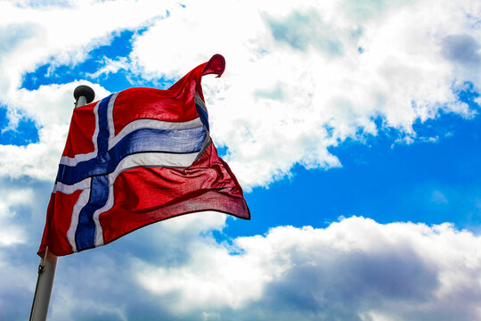 The national flag of Norway in rough wind blue sky.