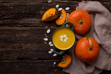 creamy pumpkin soup on wooden background.   Pumpkins, pumpkin pieces, seeds. Country style. Copy space