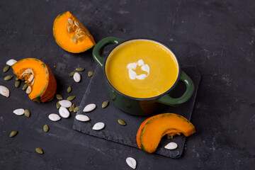 
pumpkin soup on a dark background. pumpkin slices, seeds and a whole pumpkin. Healthy eating.