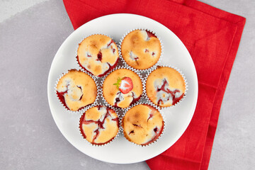 Strawberry muffin dessert on white plate on red linen napkin on gray table background