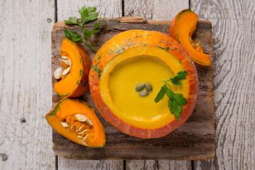 Pumpkin soup in pumpkin on a light wooden table. Healthy eating. Pumpkin. Pumpkin seeds