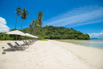 Beautiful view landscape of lounge chairs on tropical beach, the emerald sea and white sand against...