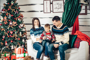 Obraz na płótnie Canvas beautiful young family with a child near the christmas tree