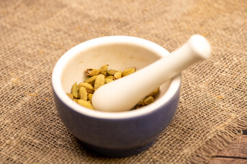 Cardamom in a ceramic mortar and pestle, close-up, selective focus.