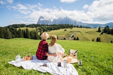 Young couple in love doing picnic visiting alps dolomities. Boyfriend and girlfriend sitting and...