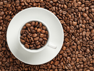 white cup with coffee beans, stand on coffee beans in soft focus, top view, copy space