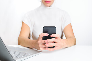 caucasian woman dressing white clothes and using an smart phone in the office