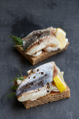 Snack - herring with dark rye bread and cream cheese on a graphite background, traditional food
