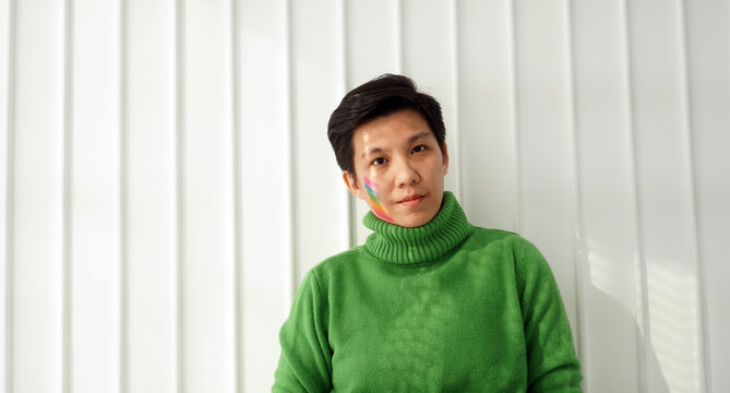 Asian ethnic handsome tomboy green sweater with pride flag paint on face support LGBT transgender