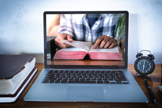 Study the bible from home, Online live church for sunday service, Laptop screen with close up reading hands, Bible on wooden table, Home church during quarantine coronavirus Covid-19, Religion concept