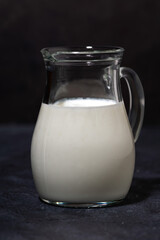 jug with fresh milk on a black background, vertical closeup