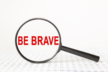 words be brave in a magnifying glass on a white background. business concept