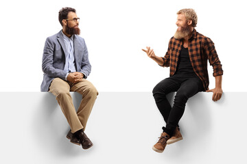 Two bearded men sitting on a white panel board and talking