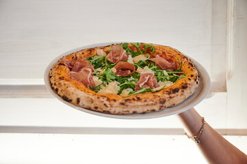Waiter holding pizza in restaurant