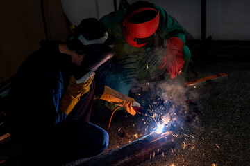 Experienced workers in the factory welding steel with electric welding machine.