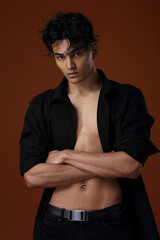 A young man with an Asian appearance in a black shirt on a brown background