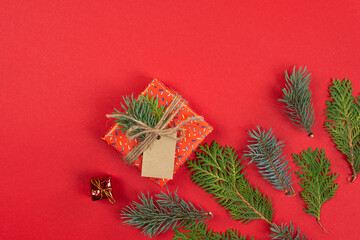 Fototapeta na wymiar Christmas background, flat lay. Fir tree branches and gift box on red background. Top view.