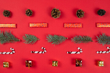 Christmas abstract pattern, flat lay. Fir tree branches, gift box and cone on red background. Concept of New Year presents