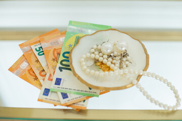 jewelry on a plate console with 100 euro bills beads and earrings
