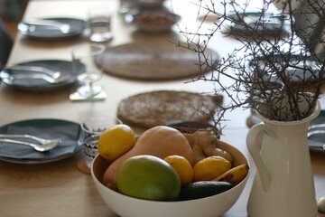 Big bowl of fruit, vase with branches and set table. Selective focus.