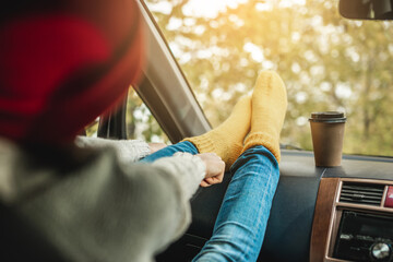 Woman in a car in warm woolen yellow socks on the car dashboard. Cozy autumn weekend trip. Concept of freedom of travel