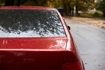 Back window of red car parked on the street in autumn rainy day, rear view. Mock-up for sticker or...
