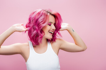 young woman touching colorful hair isolated on pink