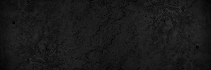 Black grunge stone background. Black concrete cement texture background. Wide banner with rough texture.