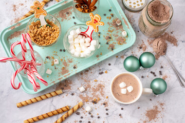 Top View of Hot Cocoa Bar with Christmas Cups and Decorations; Multiple Toppings Pictured; White and Gray Countertop
