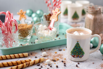 Obraz na płótnie Canvas Closeup of Hot Cocoa in a Hot Cocoa Bar with Christmas Cups and Decorations; Multiple Toppings Pictured; White and Gray Countertop
