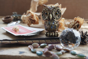 fortune-telling with cards, magic owl, dried roses, nut, birds' feather on wooden background