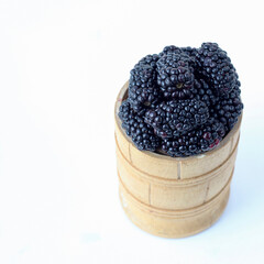 Blackberry in a wooden bowl on a white background
