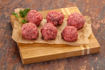 Raw meatball over wooden background