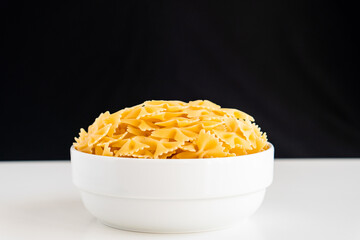 Raw dry uncooked Farfalle pasta spaghetti noodle on white bowl wooden background for basil tomato pesto sauce Homemade Italian food organic whole wheat vegan spaghetti for a healthy meal