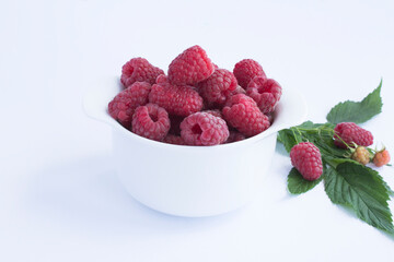 Raspberry and red currant in the white bowl on the white background closeup