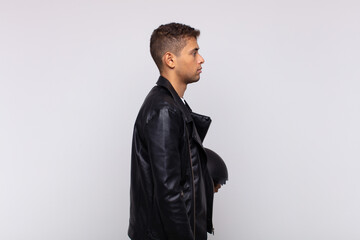 young motorbike rider on profile view looking to copy space ahead, thinking, imagining or...
