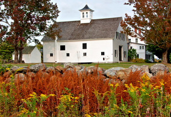 Horse farm in Jaffrey, New Hampshire. Colorful New England autumn scene with vibrant bronze-colored fern leaves, goldenrod, old stone wall, and white barn with cupola. © Jerrry G