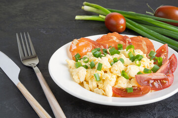 scrambled eggs with tomatoes on a white plate.
