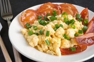 scrambled eggs with tomatoes on a white plate.